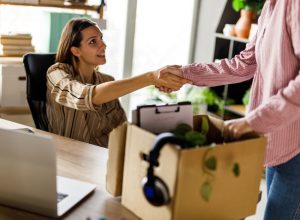 Cut out shot of unrecognizable young woman shaking hands with her boss with a box of her things from the office