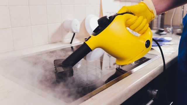 Cleaning kitchen hob with a steam cleaner.