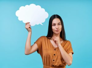 Portrait of woman holding blank paper speech cloud in hand and holding finger on chin