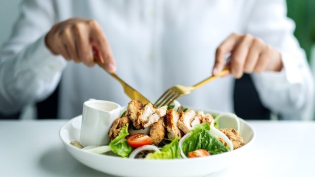 Closeup image of a man eating chicken salad on table in the restaurant