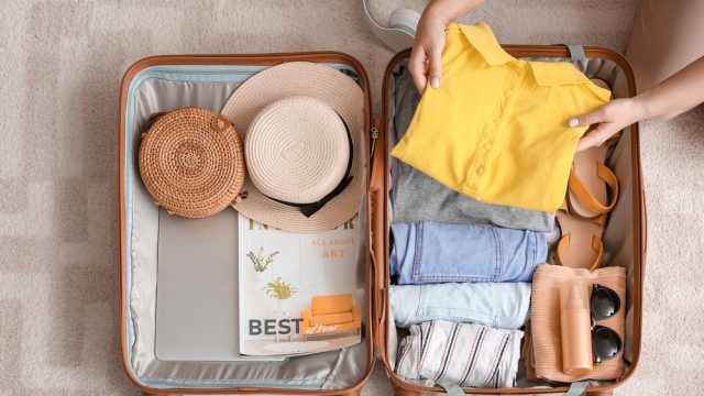 An overhead photo of a suitcase getting packed for a trip