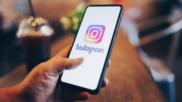 closeup of a person holding a phone with the Instagram logo on it