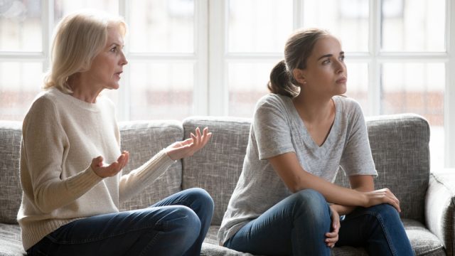 Young woman in argument with toxic mother on couch