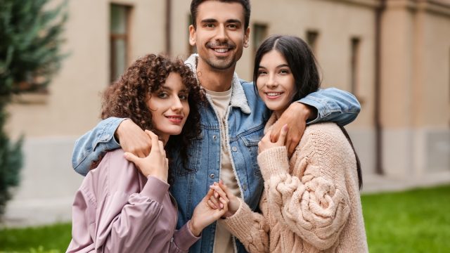 Man with two beautiful women outdoors. Polyamory concept