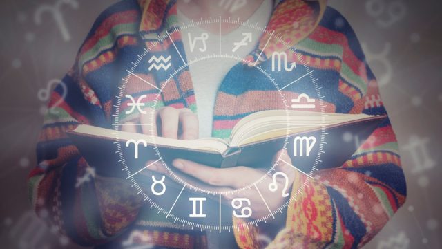 person reading an astrology book with zodiac graph imposed over photo