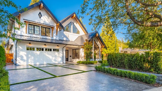 white modern farmhouse with large, stone driveway and nice landscaping
