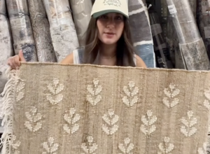 Shopper holding up a jute rug at Walmart