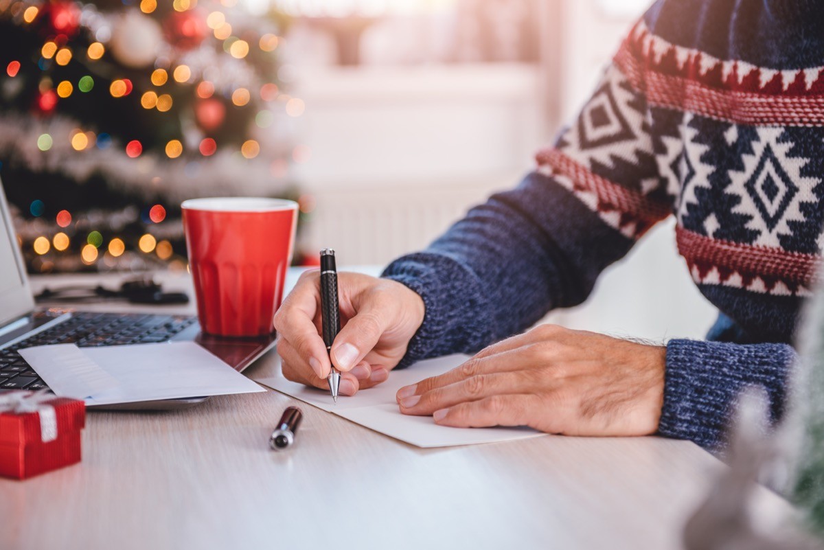 man writing holiday cards 