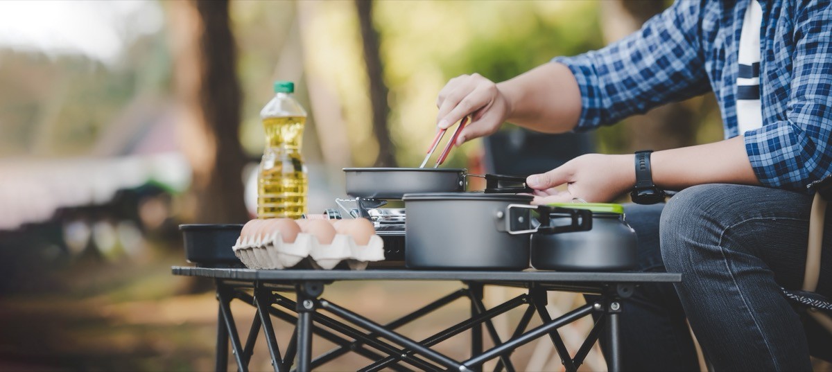 Person frying a tasty fried egg in a hot pan at the campsite.