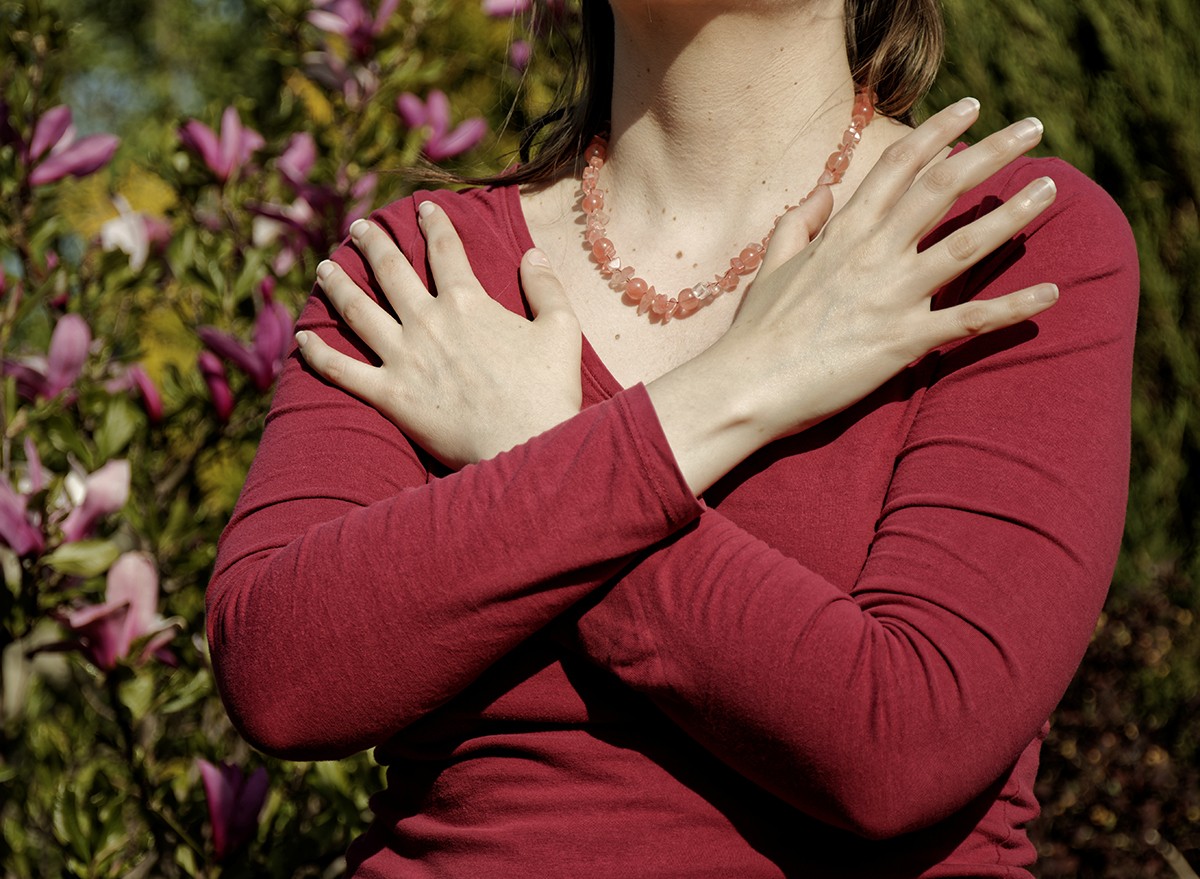 A woman touching and tapping her shoulders, crossing hands.