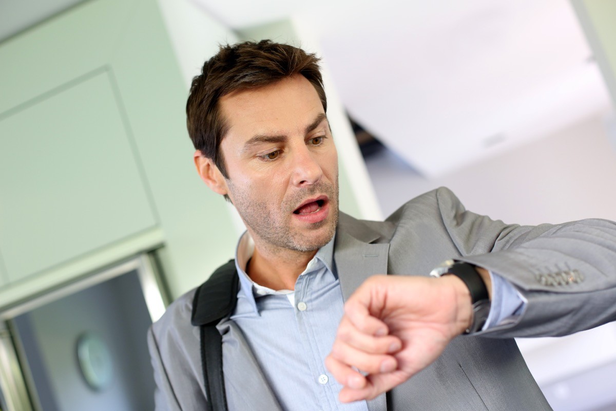 A man rushing and looking at his watch