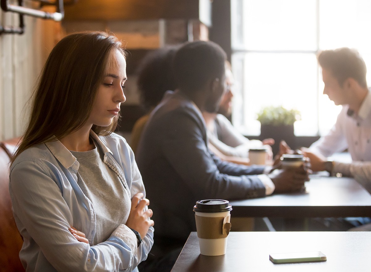 An upset woman in a coffee shop is stood up by friend cancelling