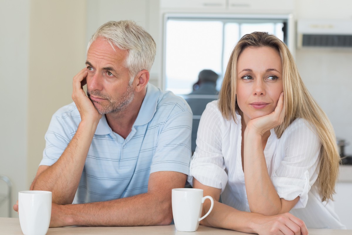 Bored couple sitting at the counter at home in the kitchen