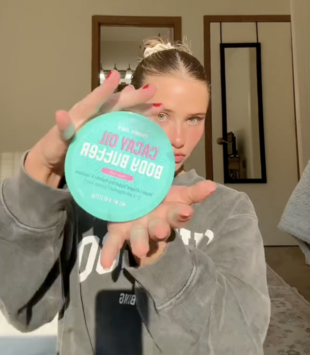 young woman holding up Trader Joe's Cacay Oil Body Butter