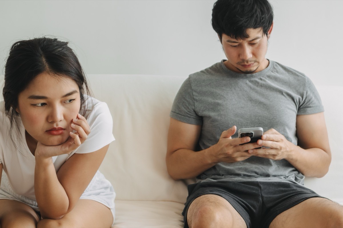 man ignoring his girlfriend while he's on his phone