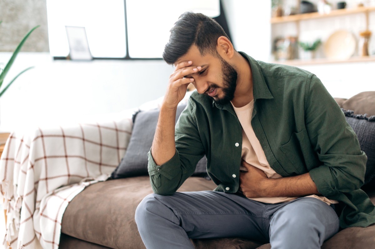 A man with stomach pain sitting on a couch