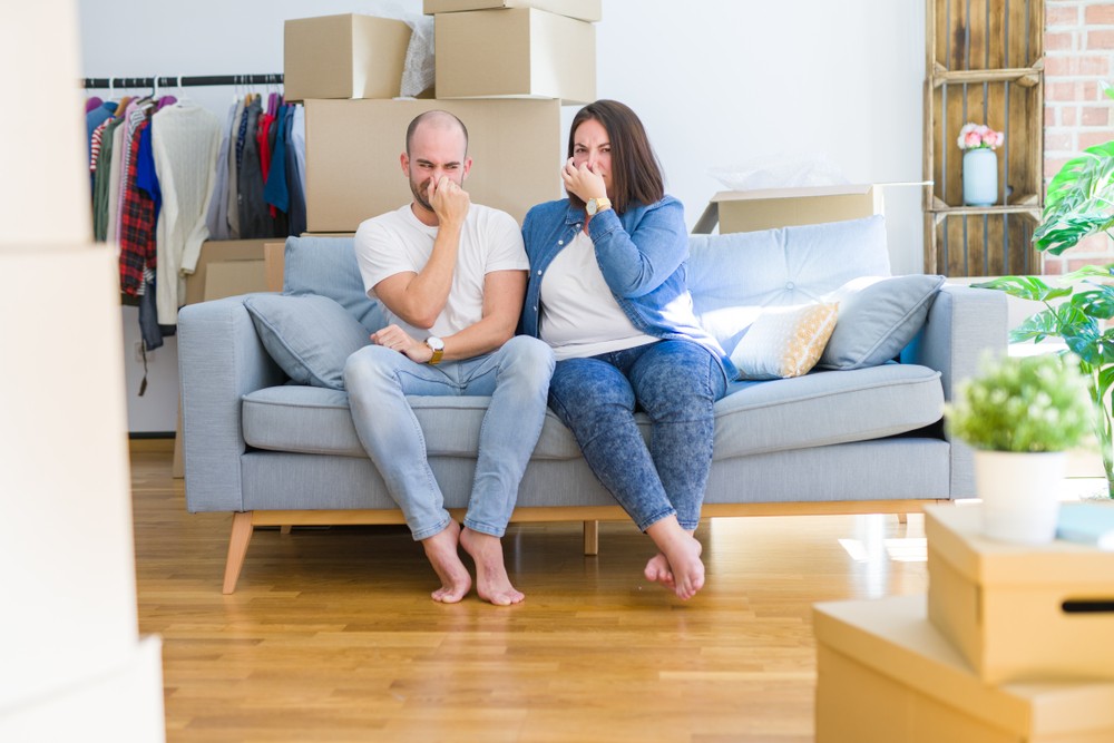 A couple sitting on a sofa holding their noses
