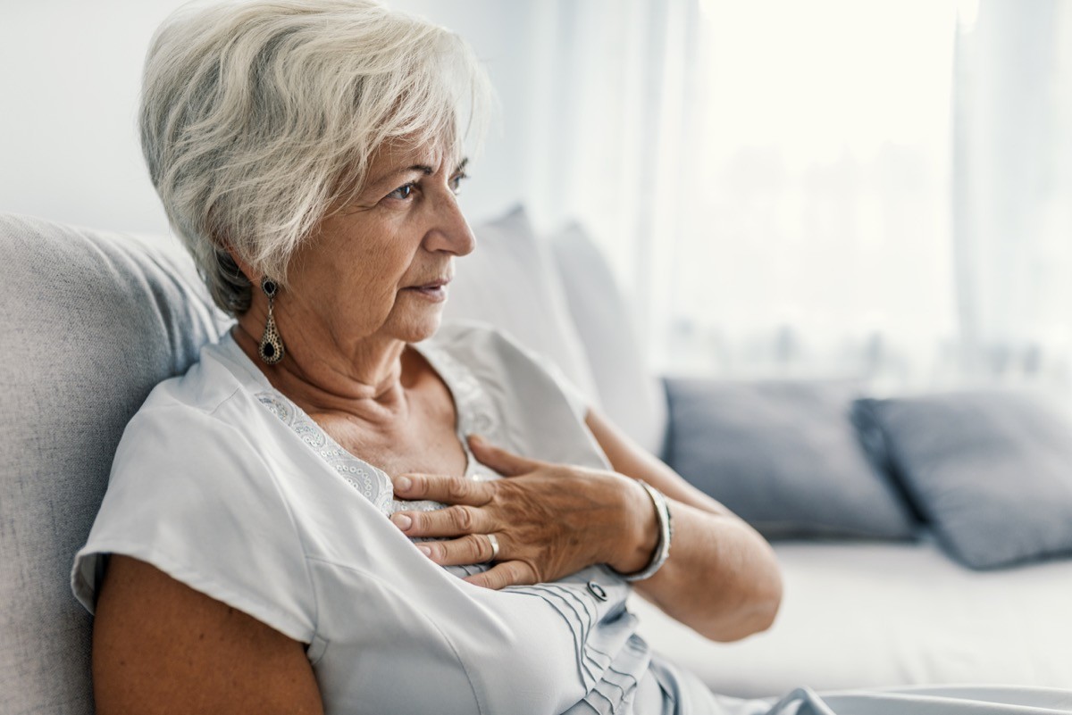Woman sitting on the couch and clutching her chest