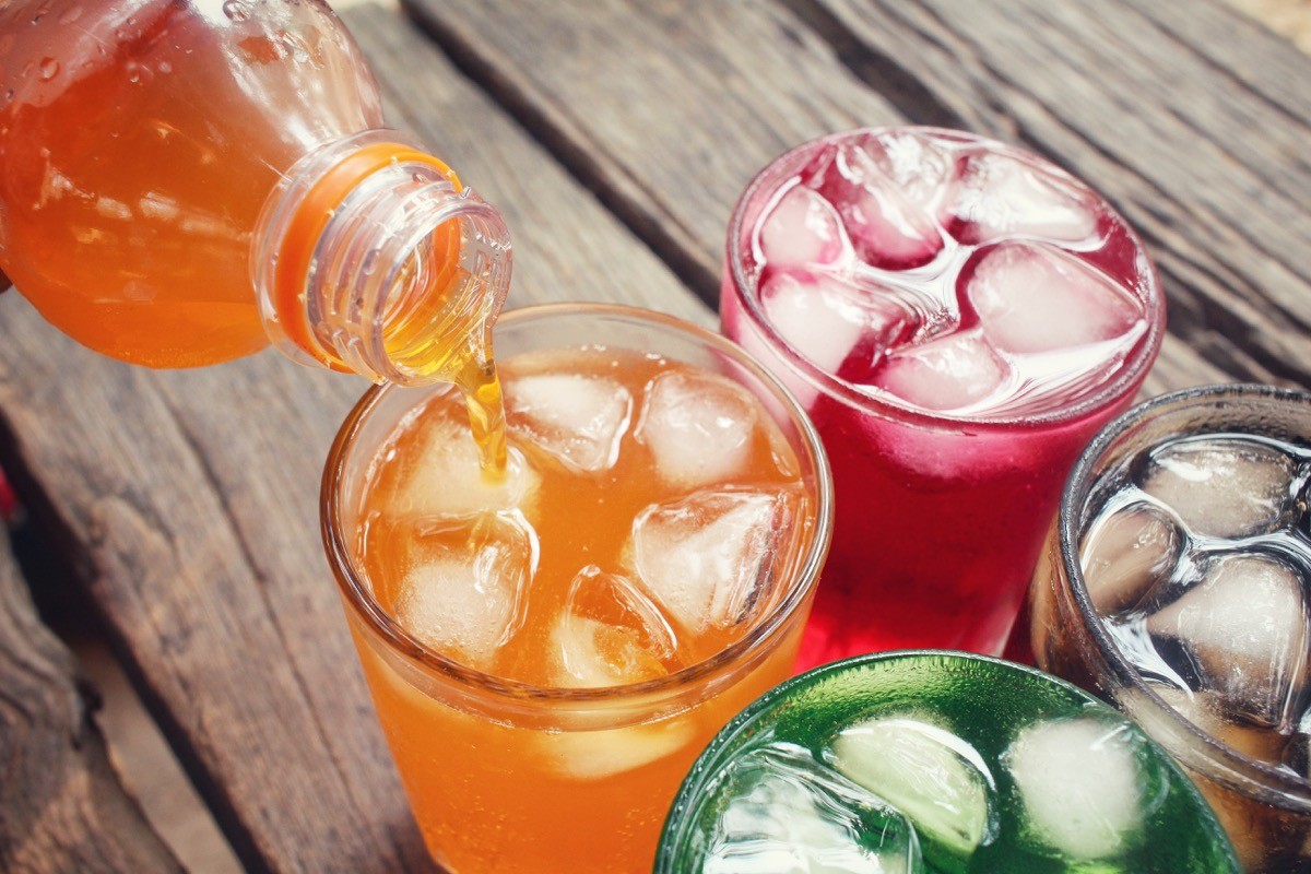 four sodas being poured on a wooden table