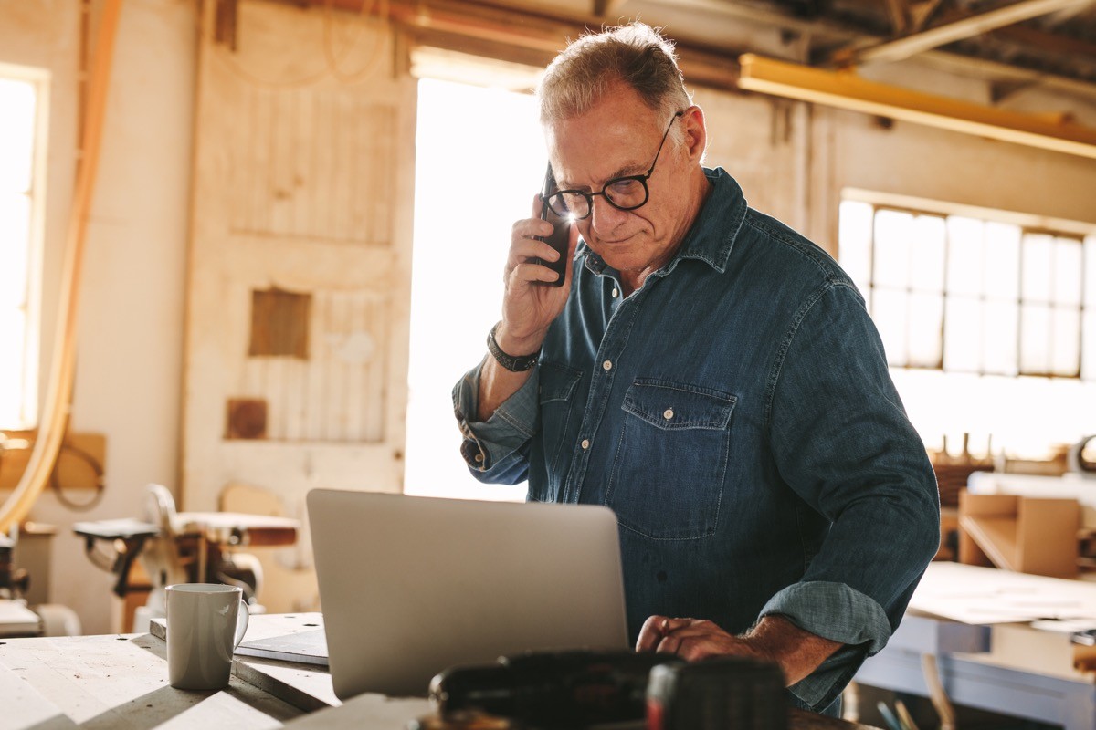 senior man talking on cell phone and using laptop
