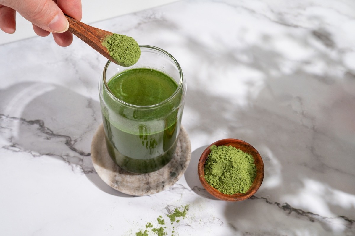 powdered greens supplement being poured into a glass of water