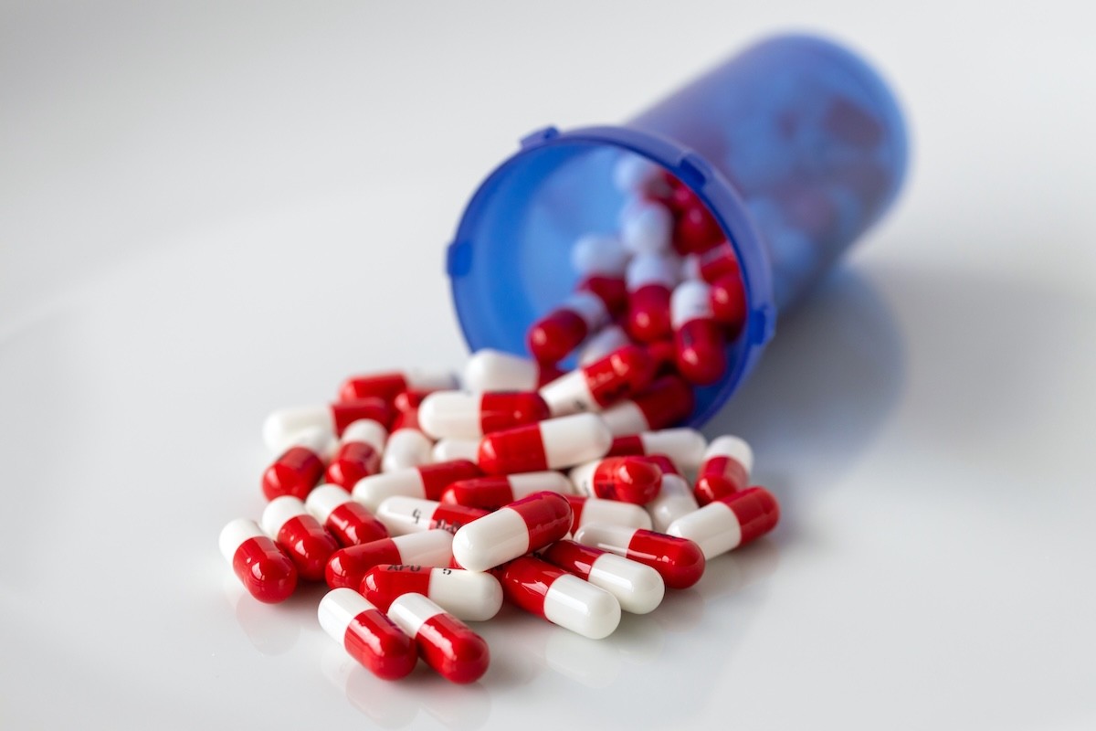 red and white Altace pills, an ACE inhibitor, spilling out of a blue bottle