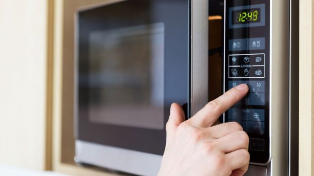hand pressing button on microwave