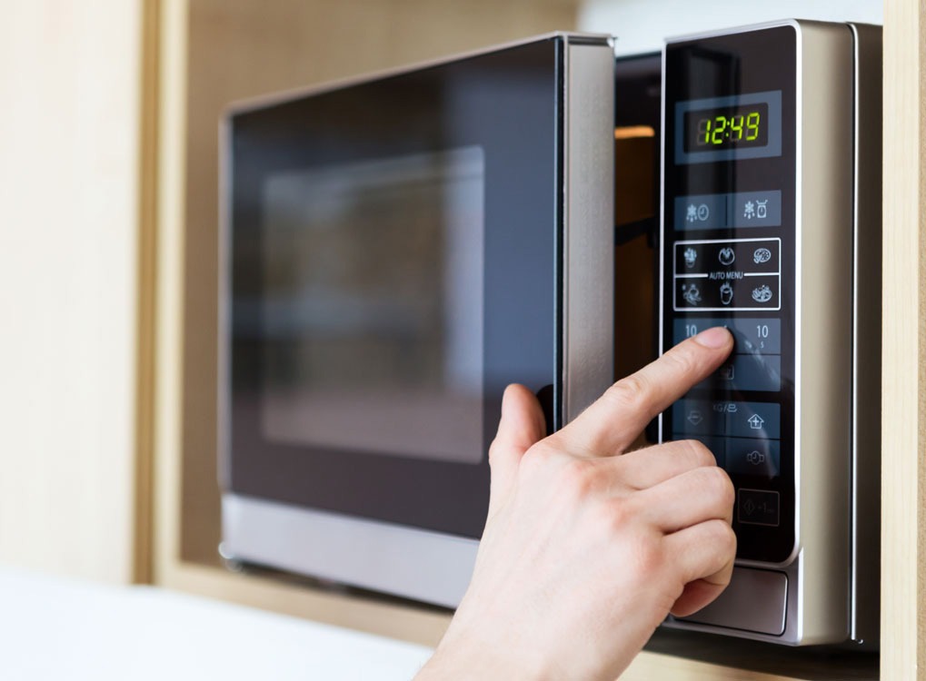 hand pressing button on microwave