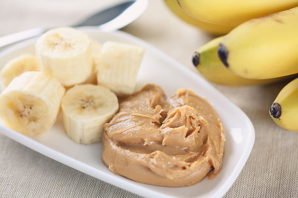A close up of sliced bananas and peanut butter on a plate